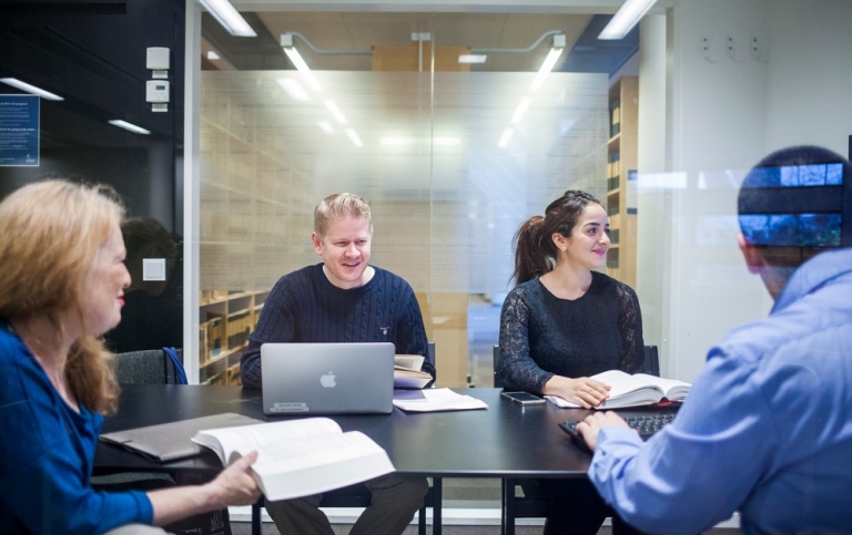 A group of students in a group room at the library.