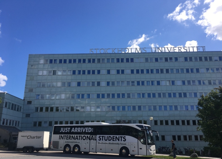 A shuttle bus outside university buildings.