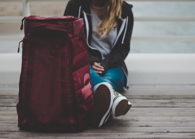 A girl sitting by a red backpack.