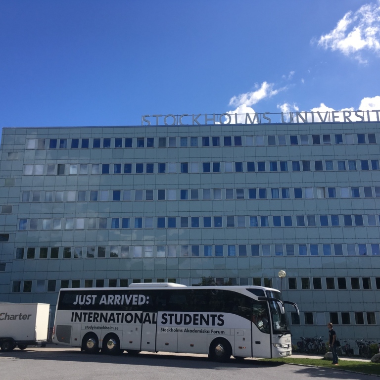 A shuttle bus outside university buildings.